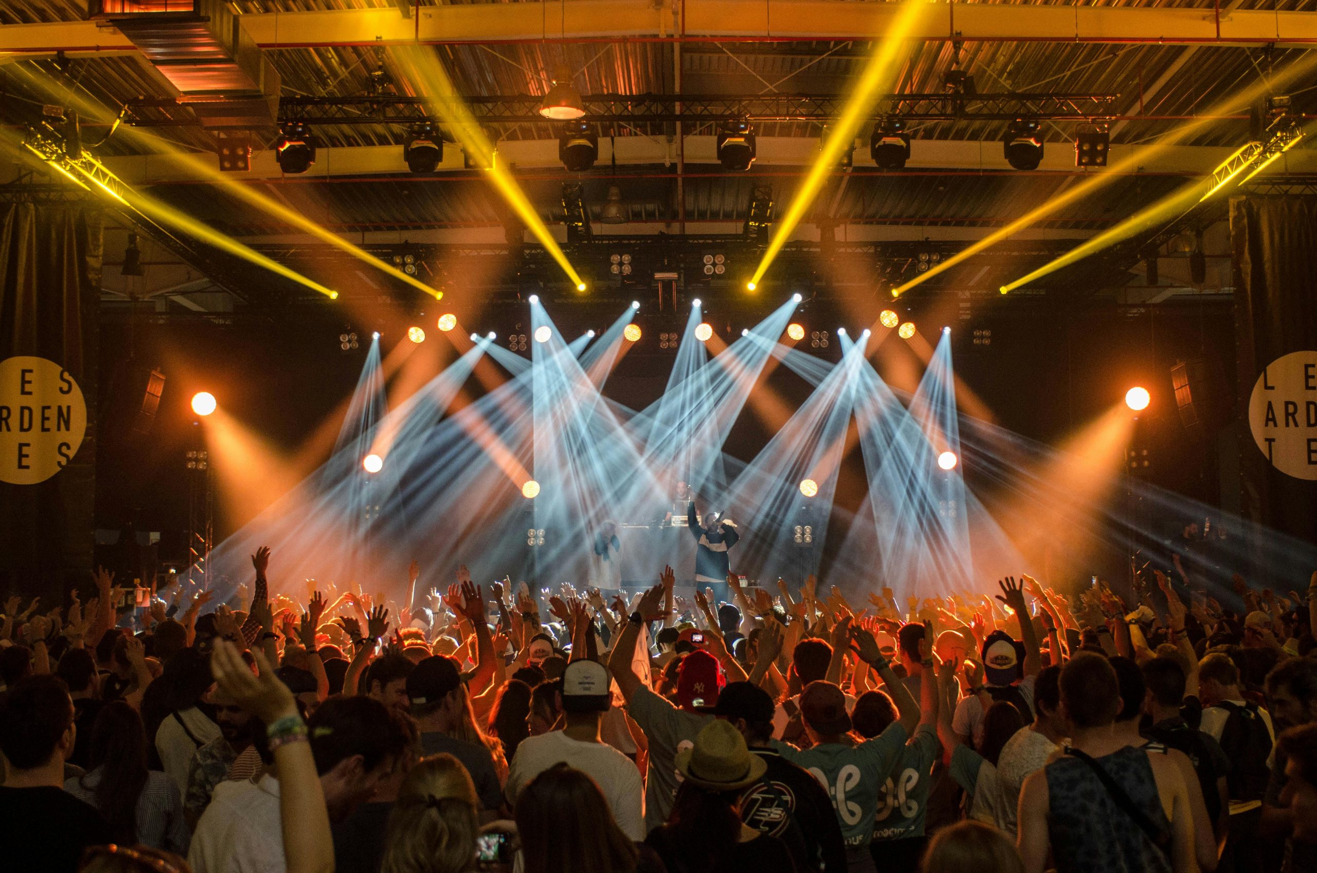 Energetic music concert scene with bright lights and a lively cheering crowd indoors.