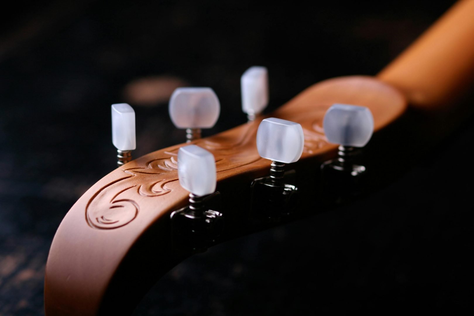 Artistic close-up of a guitar headstock showcasing engraved design, emphasizing craftsmanship and elegance.