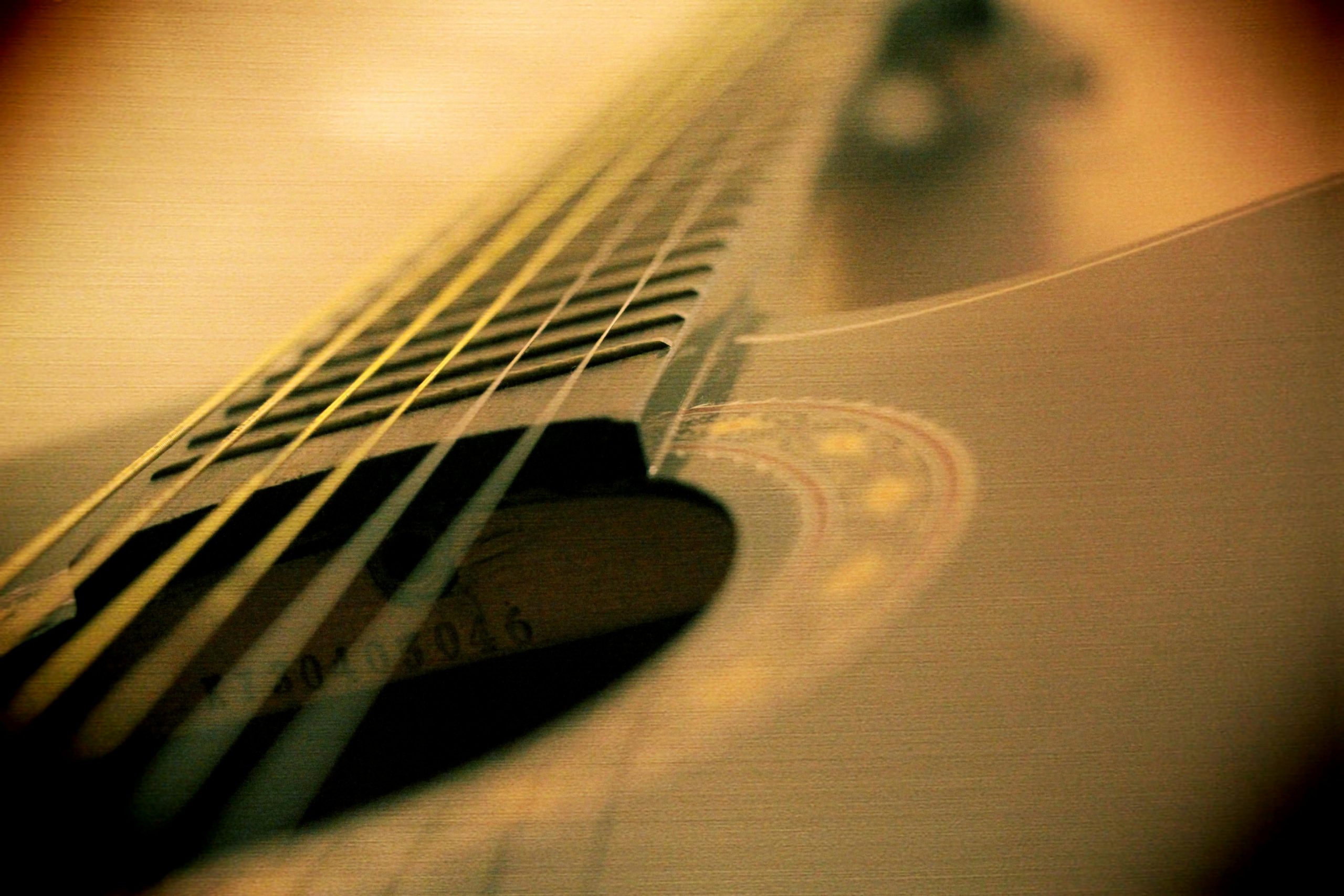 Blurred artistic close-up of a guitar fretboard highlighting strings.